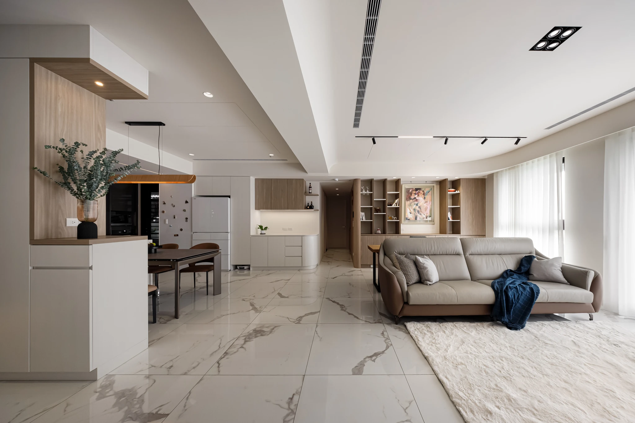 Akuma Design｜惠宇青山清 — 客廳全景，米白石英磚地坪連貫餐廚開放格局，L形沙發與餐桌椅映於自然採光｜空間攝影 / 琢磨影像