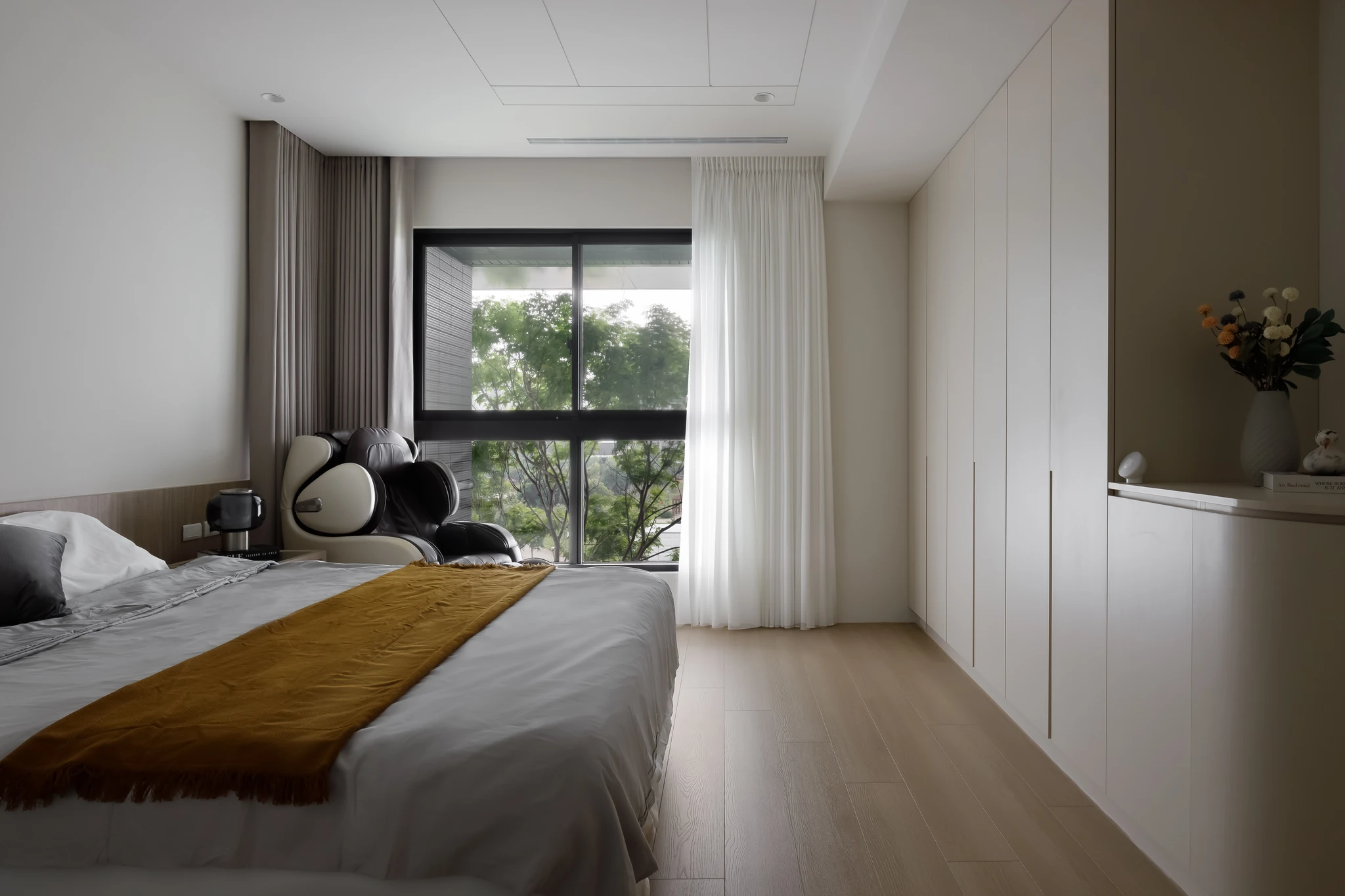 Akuma Design｜惠宇青山清 — 主臥室全景，雙人床組配芥黃床旗，大面落地窗外透入台中綠樹景觀｜空間攝影 / 琢磨影像