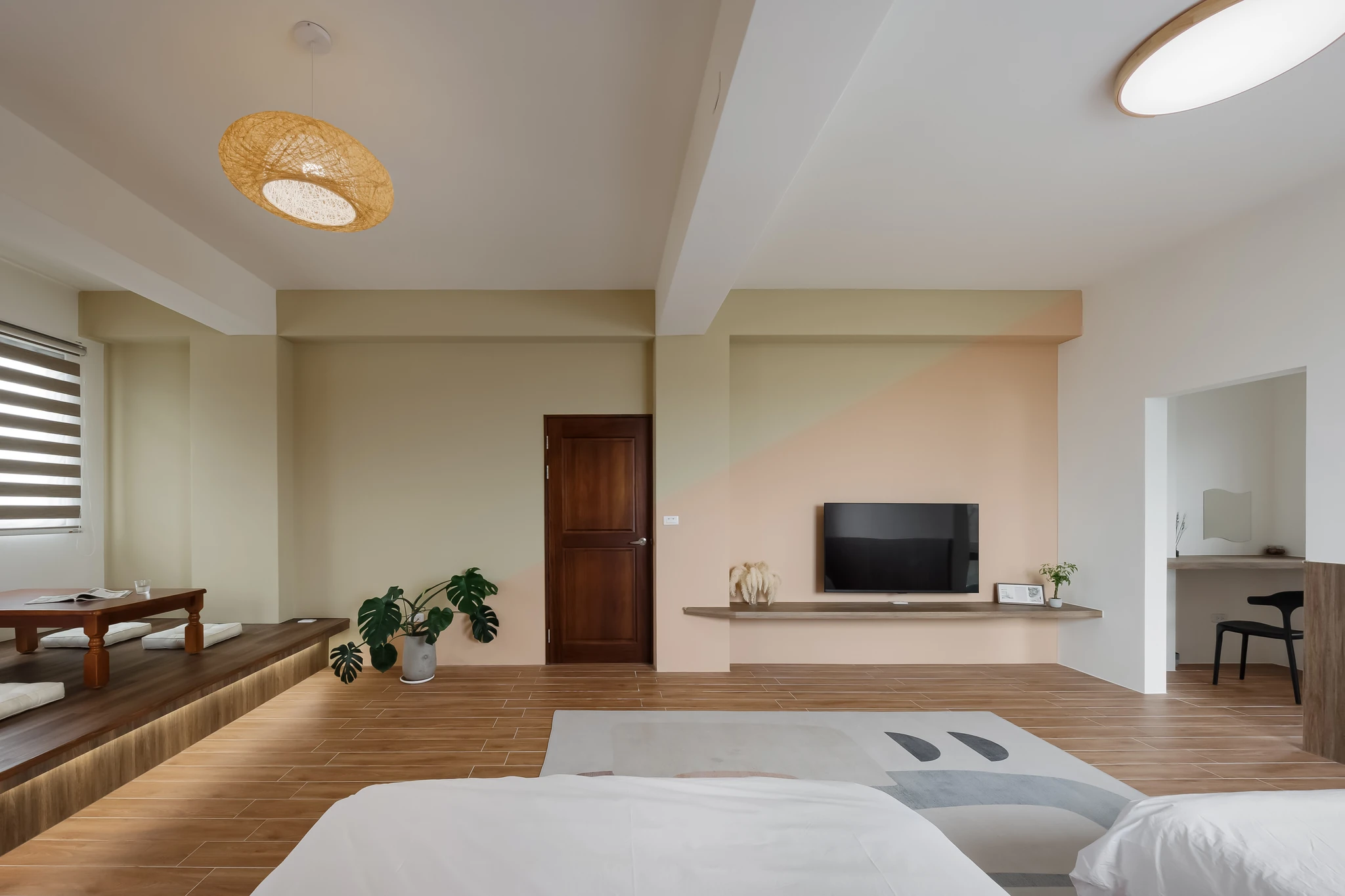 傑輝設計｜花蓮度假私宅 — 套房場景，木作架高和室與暖膚色電視牆相鄰，胡桃木門與木質地坪串連，通往拱形梳妝端景，展現層次豐富的住宅設計｜空間攝影 / 琢磨影像