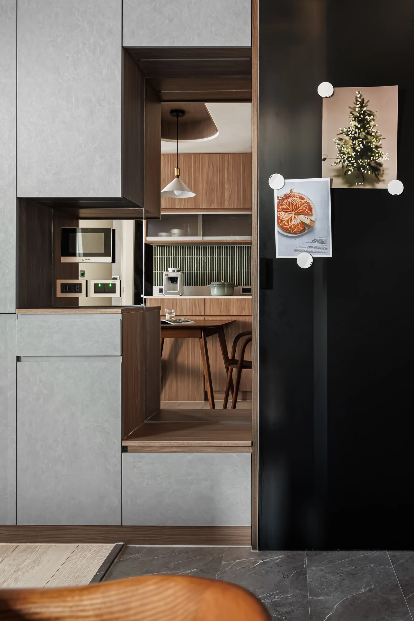 YJ Design|富宇富好 — 廚房入口灰色櫃體與黑色烤漆牆,框景望向木質吧檯區|空間攝影 / 琢磨影像