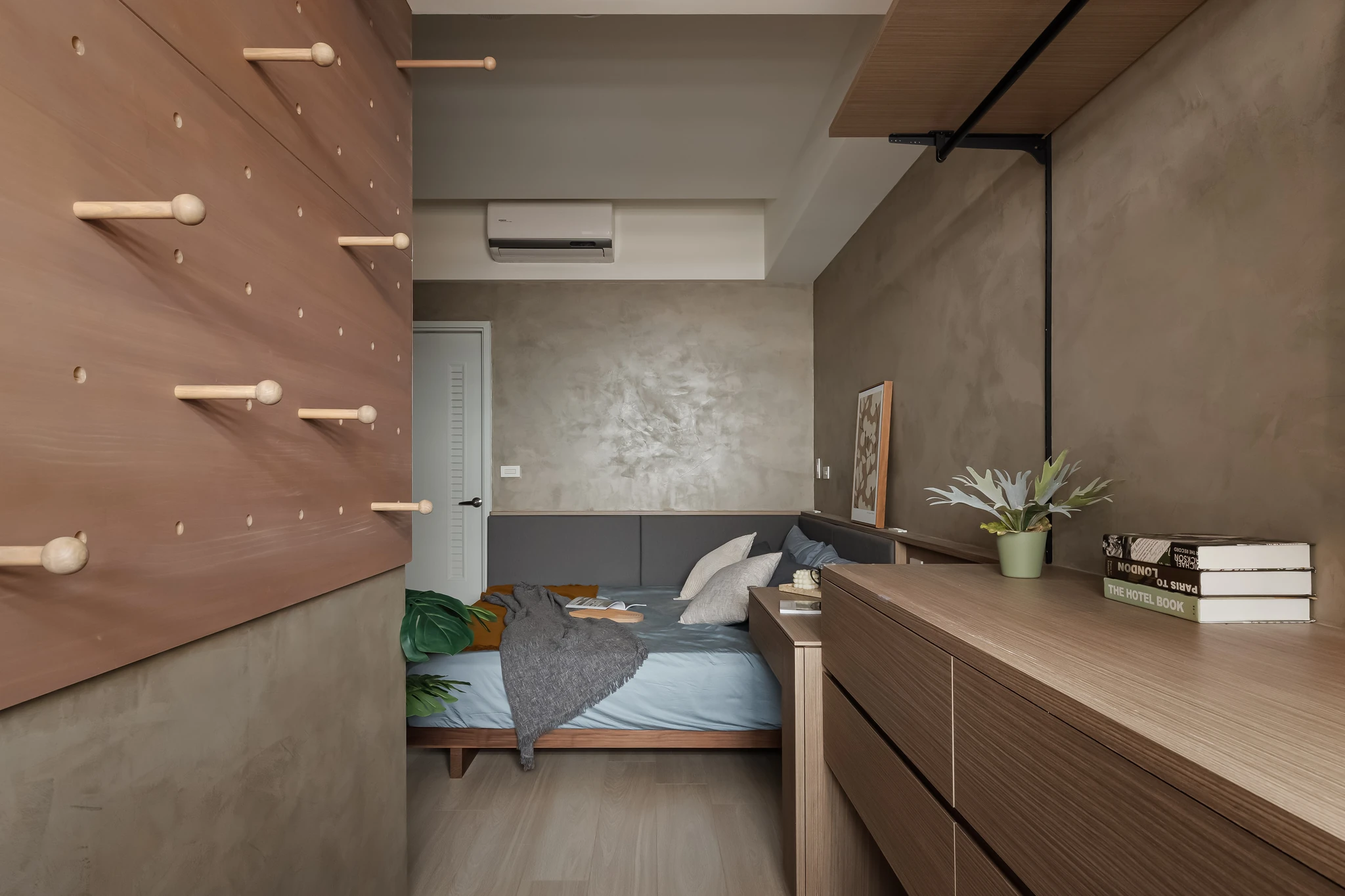 YJ Design｜陽光樹 — 木質洞洞掛牆走道望向臥床，灰泥牆面與懸浮木作櫃檯面｜空間攝影 / 琢磨影像