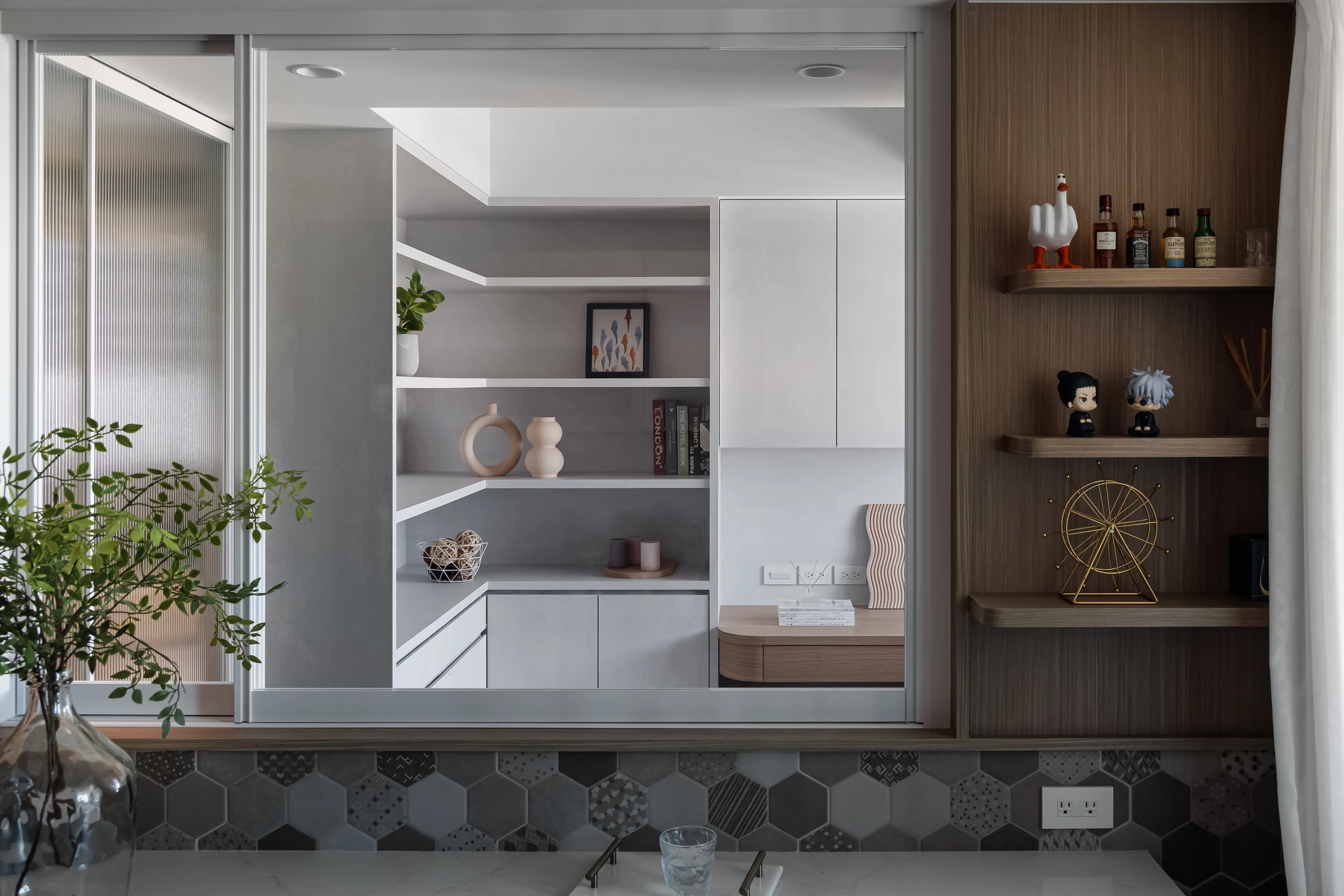 YJ Design｜陽光樹 — 吧檯望向白色餐櫃收納區，玻璃窗框景與木質展示層架、六角磚檯面｜空間攝影 / 琢磨影像